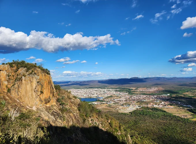 Vista de um vale da Caatinga com vegetação e cidade ao fundo
